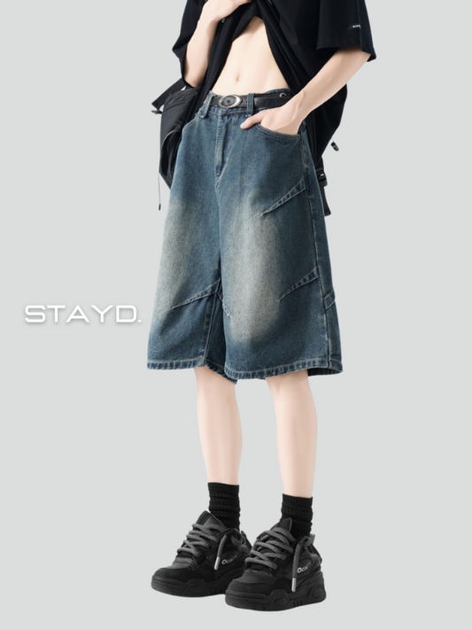 立体カッティングが特徴のウォッシュブルーデニムショーツを着用したモデル。STAYDのユニセックスな韓国ストリートファッション。