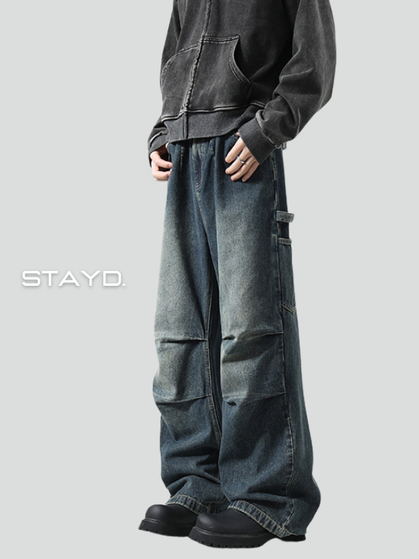 STAYDのロゴ入りカットで、ルーズシルエットのカーゴデニムパンツを穿いたモデルが横向きに立つ韓国系カジュアルコーデ